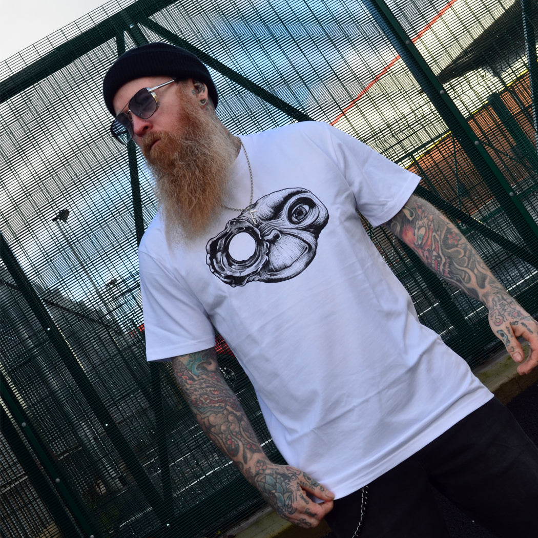 Man wearing a white t-shirt with an ET Terminator mashup design, standing in front of a metal fence.