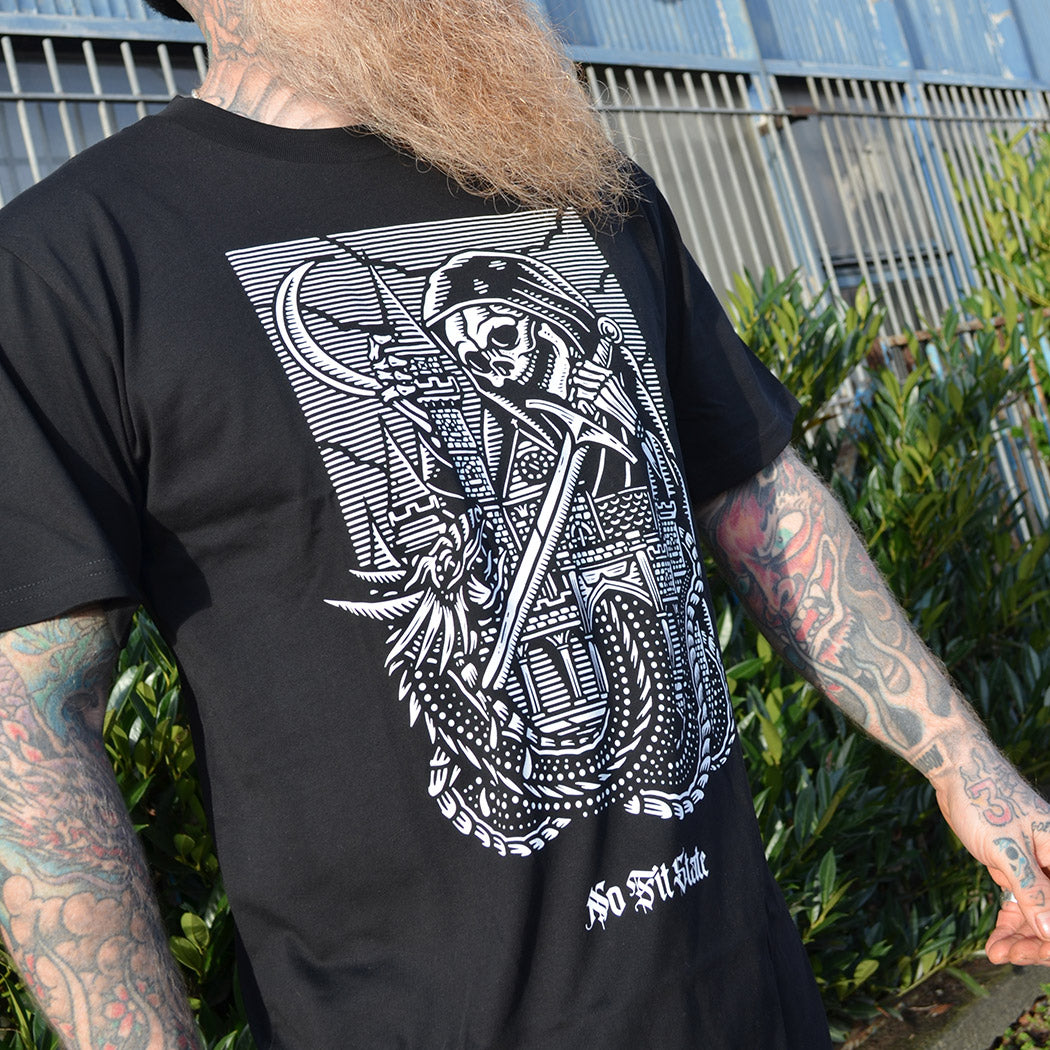 Person wearing a black t-shirt with a white medieval skull design, standing outdoors.