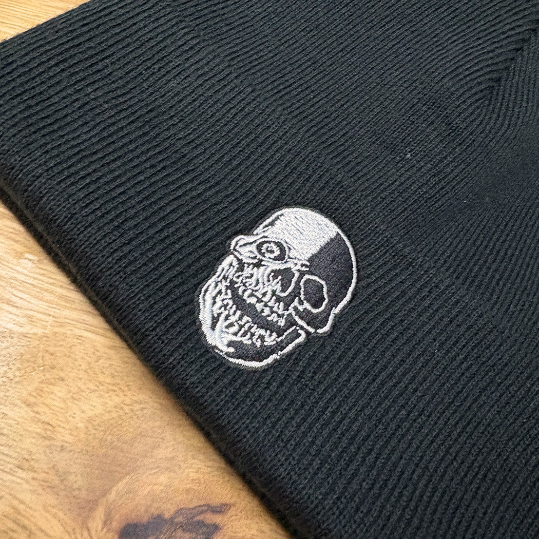 Black beanie with a white embroidered skull design