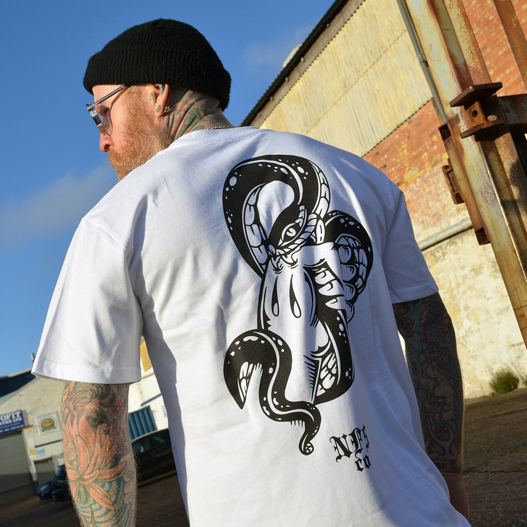 Man wearing a white t-shirt with a black snake illustration on the back, standing outdoors.
