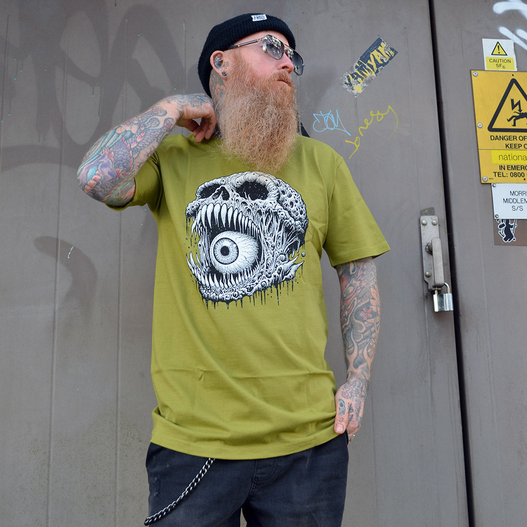 Man wearing a green t-shirt with a skull illustration, standing in front of a door.