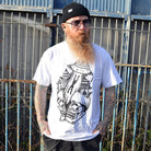 Man wearing a white t-shirt with a graphic design in front of a metal fence.