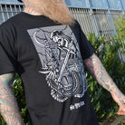 Person wearing a black t-shirt with a white medieval skull design, standing outdoors.